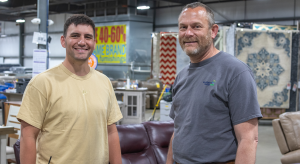 Two men posing in front of furniture for sale