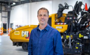 Man smiling in front of heavy machinery